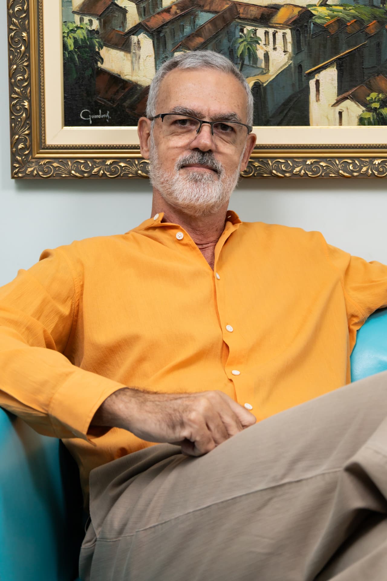 Dr. Francisco sentado em poltrona, de camisa laranja, em clima descontraído